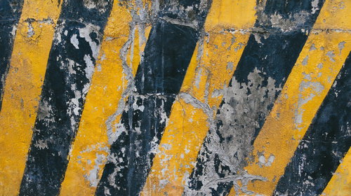 ヒビが入り塗装が落ちた黄黒の警告表示パターン
