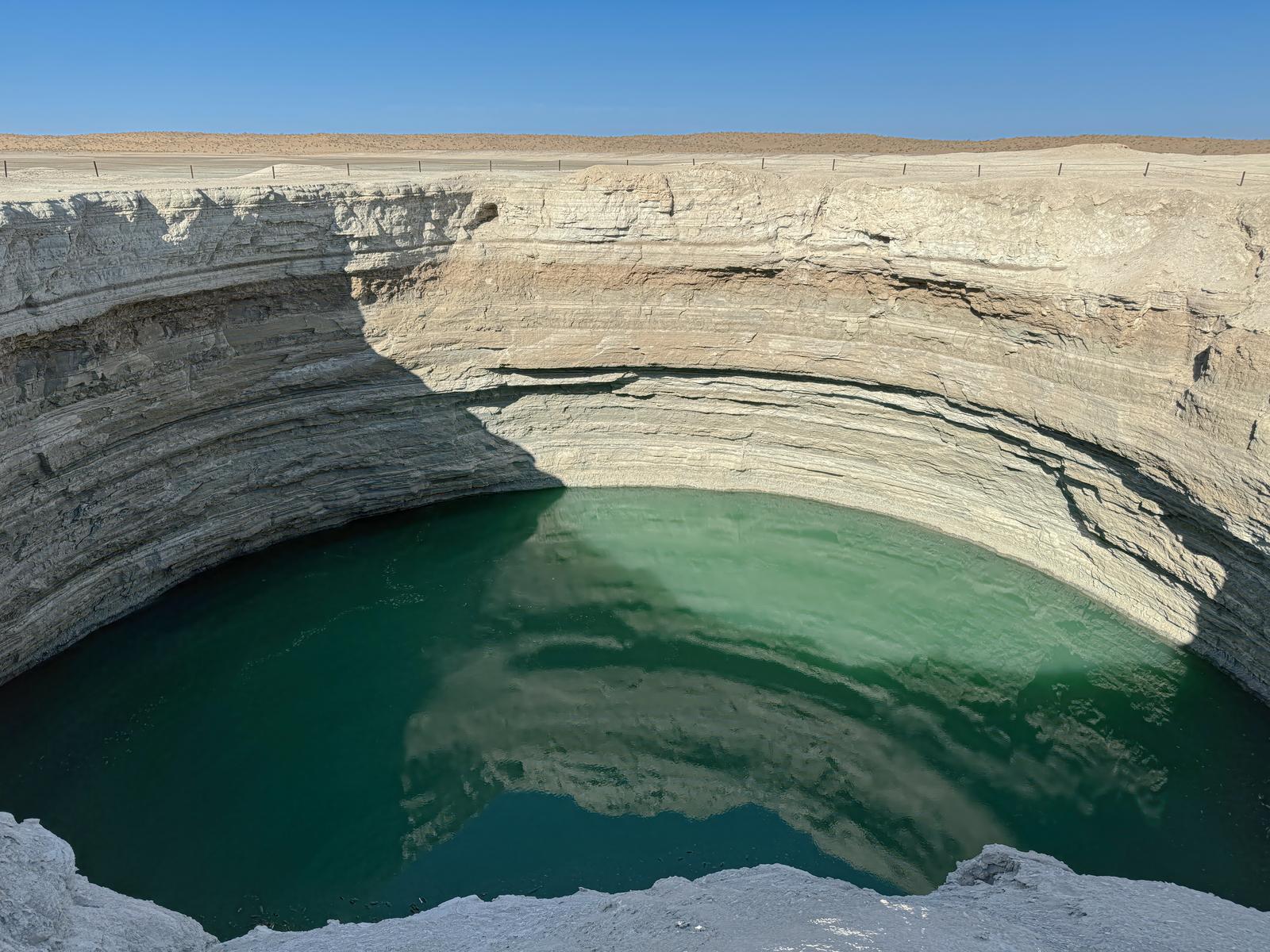トルクメニスタンのクレーターに溜まった緑色の水と白い石灰岩の崖