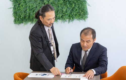 印刷した資料を見ながら指摘する男性社員の打ち合わせシーン