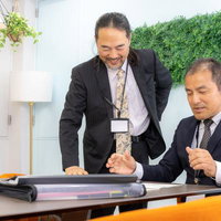 会議後にオフィスで和気あいあいと談話する管理職の男性の写真