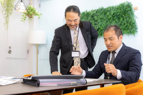 会議後にオフィスで和気あいあいと談話する管理職の男性