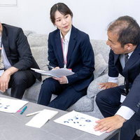 ソファーに座りながら資料を広げてブレストする社員の写真