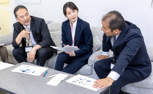 ソファーに座りながら資料を広げてブレストする社員