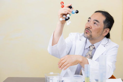 分子モデルを片手に掲げて研究する白衣の博士