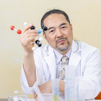 分子モデルを手に説明する研究をしている教授風の男性の写真