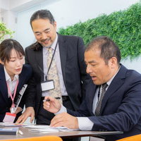 転職したばかりの中途採用に紙の資料で説明する女性と役員たちの写真