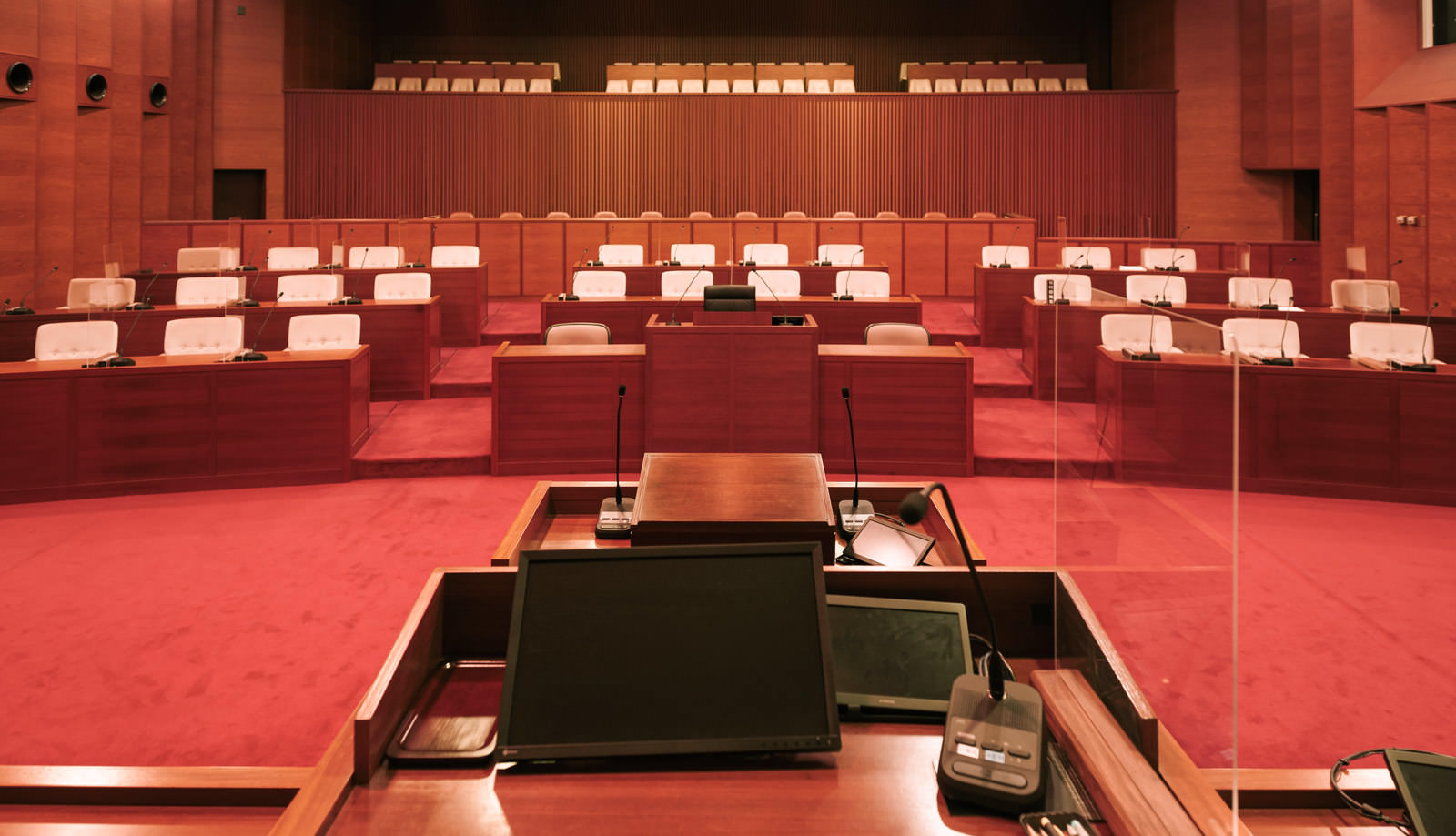 赤い絨毯が敷かれた議場に複数の議員席が並ぶ津山市議会の議場