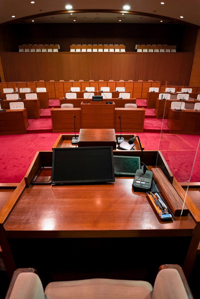 議長席から見た市議会議場。木製席が階段状に並び、赤紫のカーペットが敷かれている
