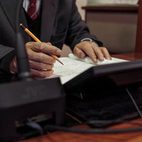 津山市議会の議場で資料に書き込みをするスーツ姿の男性議員の写真