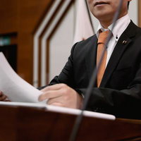 市議会議場で書類を読み上げる市議会議員の発言風景の写真
