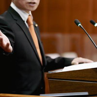 演壇で手を前に伸ばし発言する津山市議会議員の写真