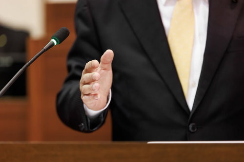 市議会で登壇する議員の身振りと市議会のマイク
