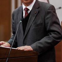 資料を手に演壇で熱弁する津山市議会の議員の写真