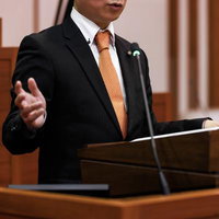 津山市議会の演壇で手振りを交えて発言する議員の姿の写真