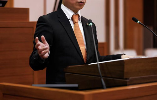 津山市議会の演壇で手振りを交えて発言する議員の姿