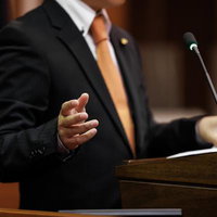 津山市議会の演壇で手振りを交えながら発言する議員の写真