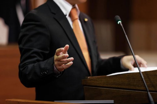 津山市議会の演壇で手振りを交えながら発言する議員