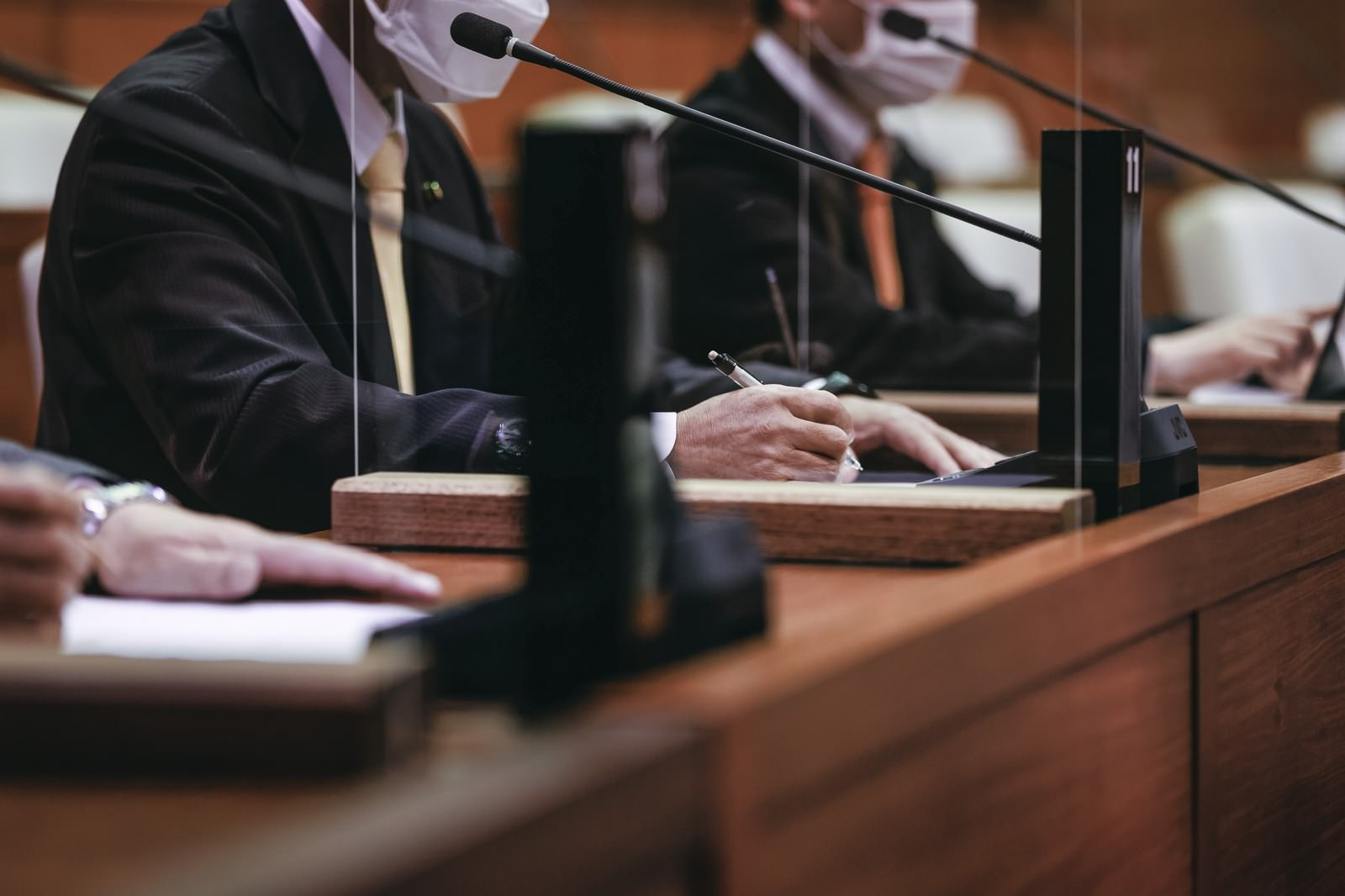 議席でメモを取りながら議論に参加する市議会議員