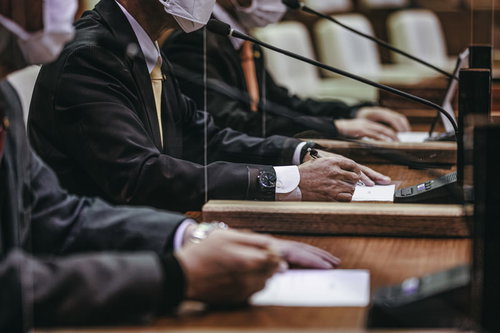 議員席で議論する市議会議員がマイクの前で熱弁を振るう場面