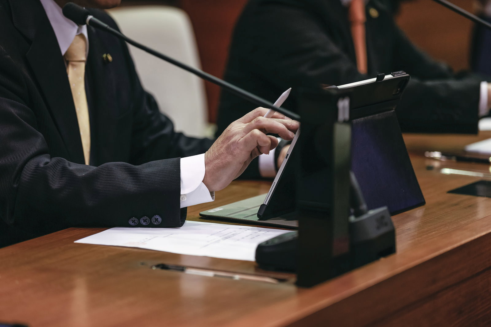 紙資料を見ながらタブレットを操作する議会の男性議員