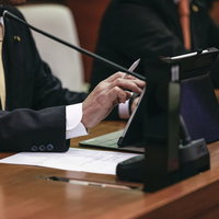 紙資料とタブレットを併用する津山市議会の議員の写真