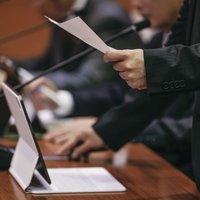 タブレット端末導入後も紙資料を併用して議論する津山市議会議員の写真