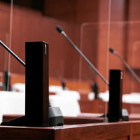 議席に配置された議員番号入り氏名標とマイクの議場風景の写真