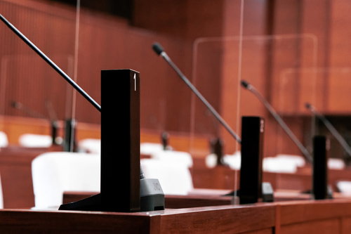 議席に配置された議員番号入り氏名標とマイクの議場風景