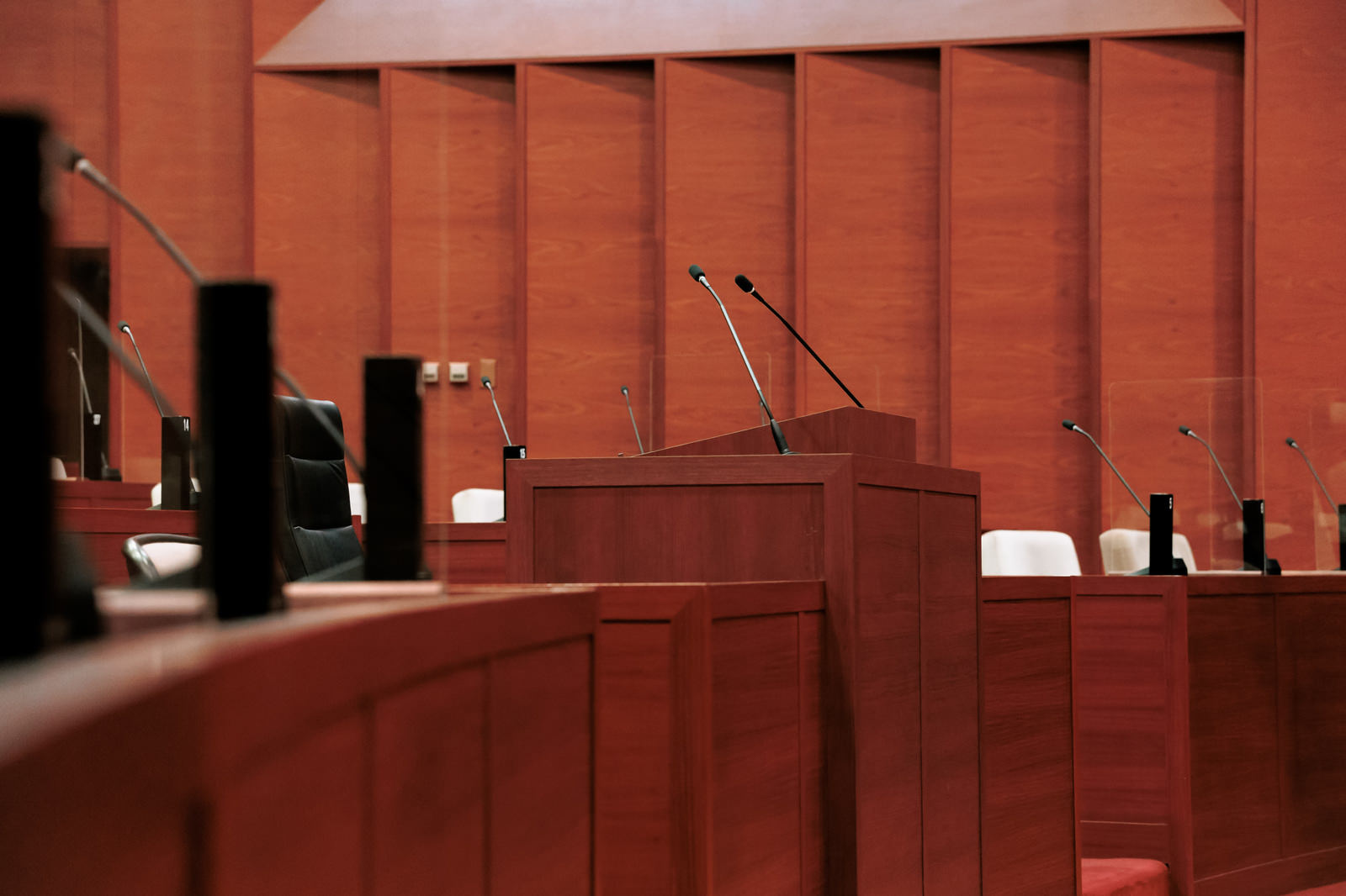 赤茶色の議場に設置された木製の質問席とマイクロフォン