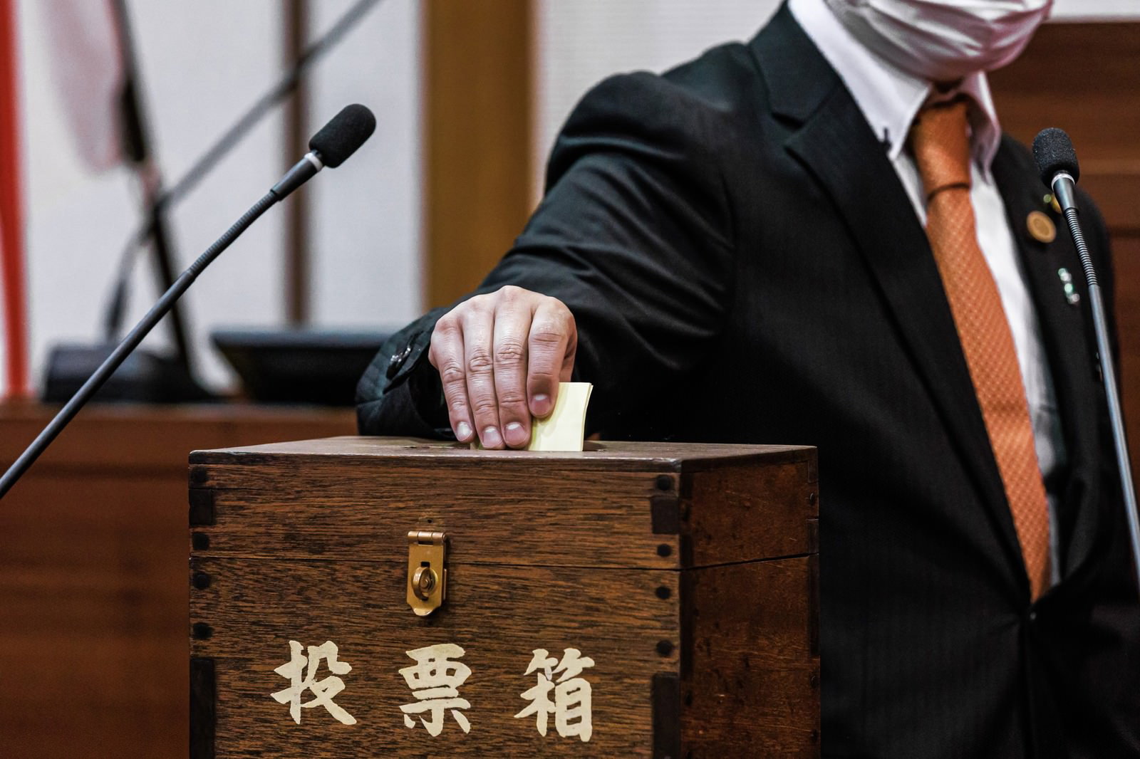 投票箱に投票用紙を入れるマスク姿の議員