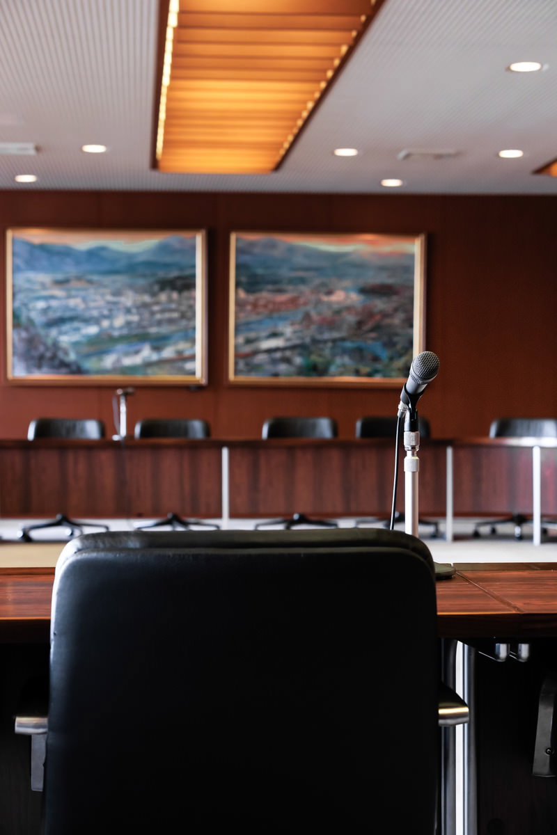津山市議会の議場内部。木製の議員席が並び、中央にはマイクが配置されている