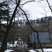 初冬の戸隠神社奥社入り口付近と奥にそびえる雪をまとった戸隠の山々の写真