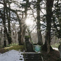 周囲に雪の残る頭上に太陽をいただいた一龕龍王祠(いっかんりゅうおうし)の写真