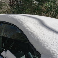 フロントガラスまで雪に覆われた乗用車の写真