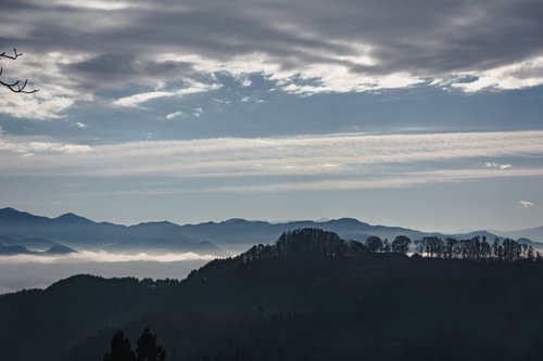 ややかすんで見える葛山城（かつらやまじょう）跡と奥に広がる雲海と連なる山々