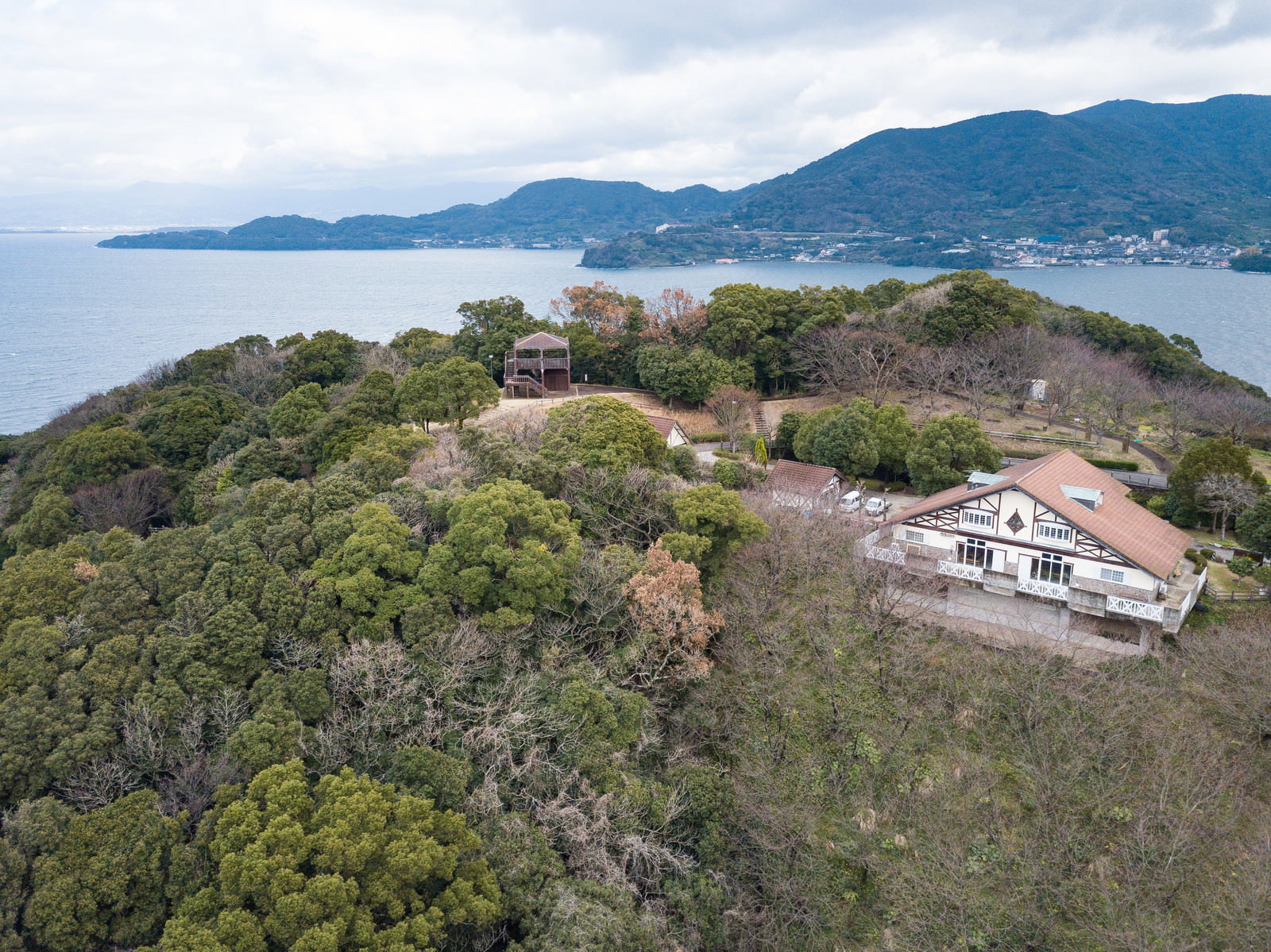 山頂の崎野自然公園を空撮した景観、海と山を背景にキャンプ場施設が点在