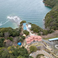 崎野自然公園キャンプ場の赤い屋根コテージと海岸の空撮の写真