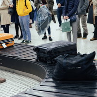 空港のバゲージクレームでターンテーブルから受け取るキャリーケースの写真
