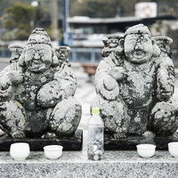 時津港付近の石段に鎮座する恵比寿像と狛犬のような石像の写真