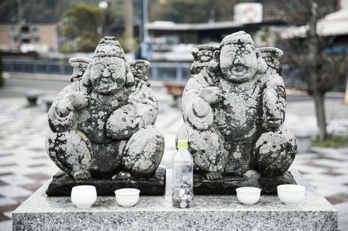 時津港付近の石段に鎮座する恵比寿像と狛犬のような石像