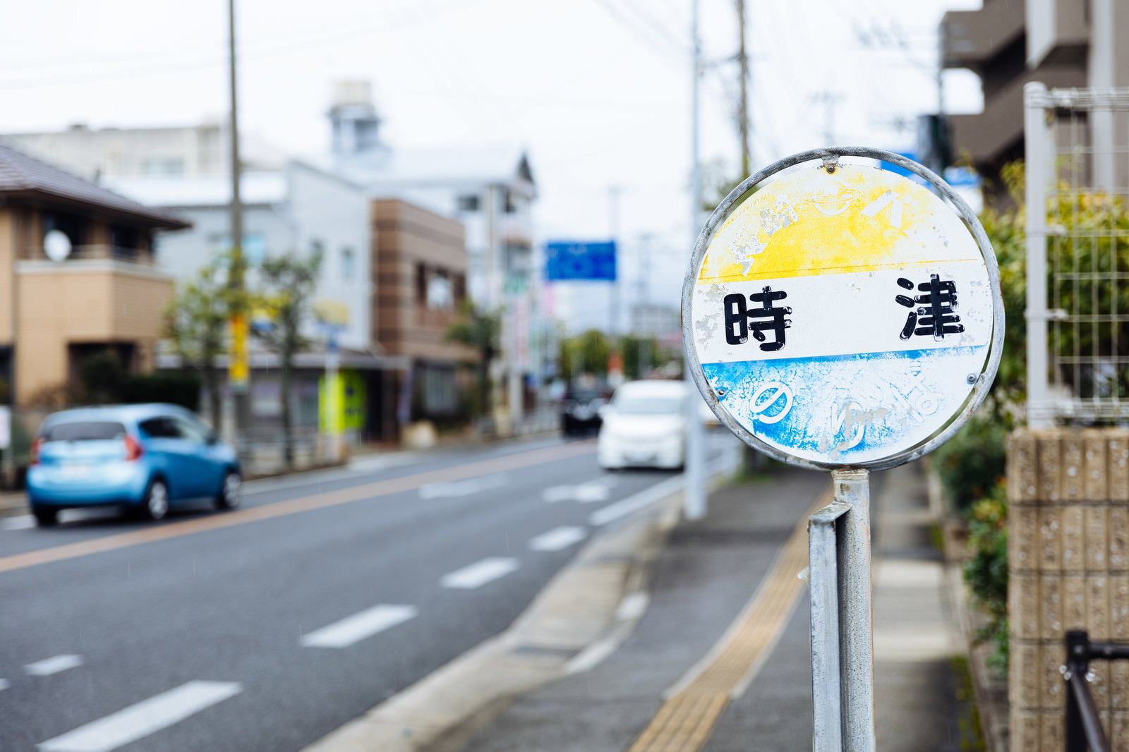 時津と書かれた青い円形のバス停留所標識と住宅街の風景