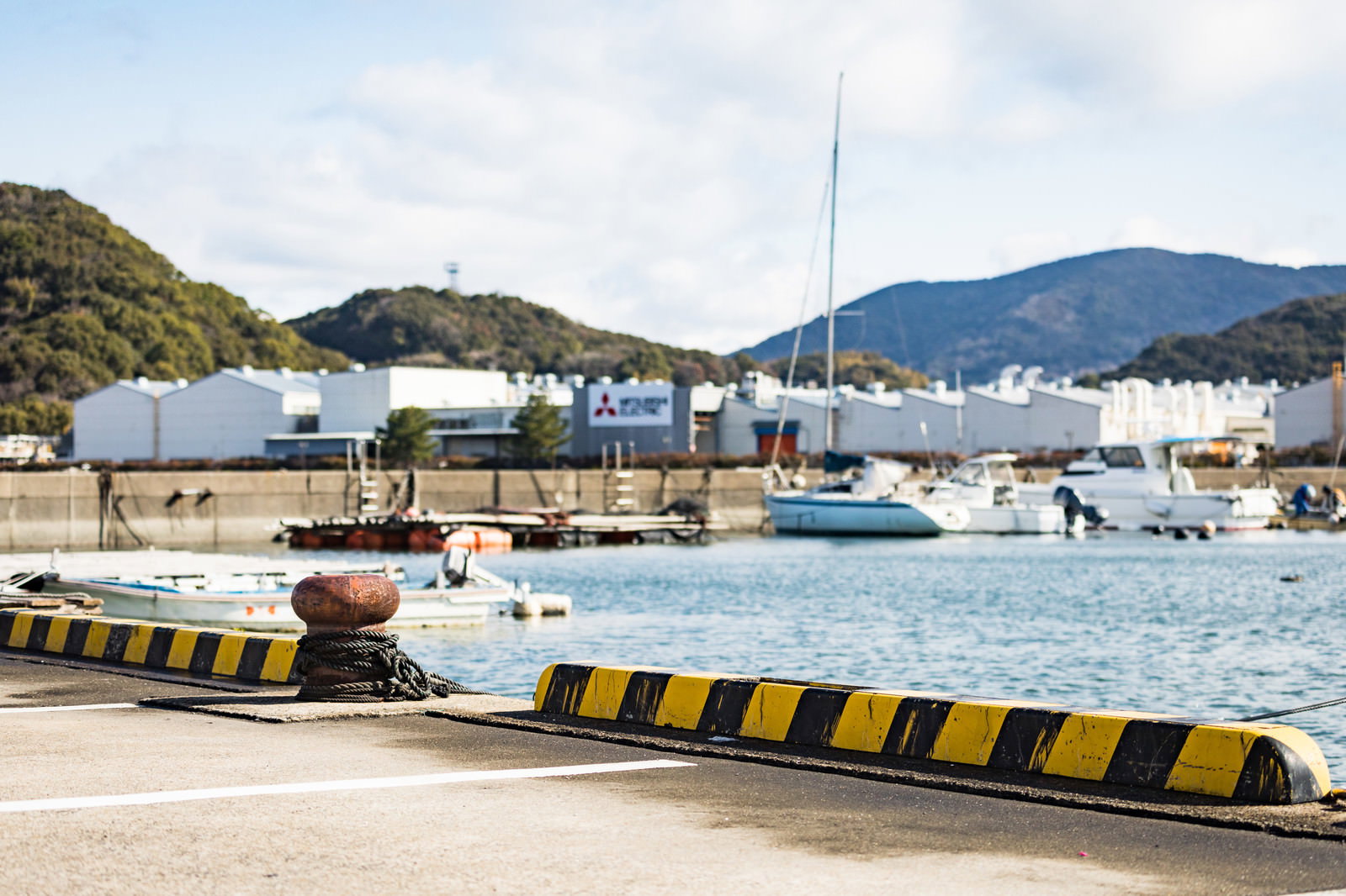 大村湾漁協組合の漁港に停泊する白い漁船と背景の山々