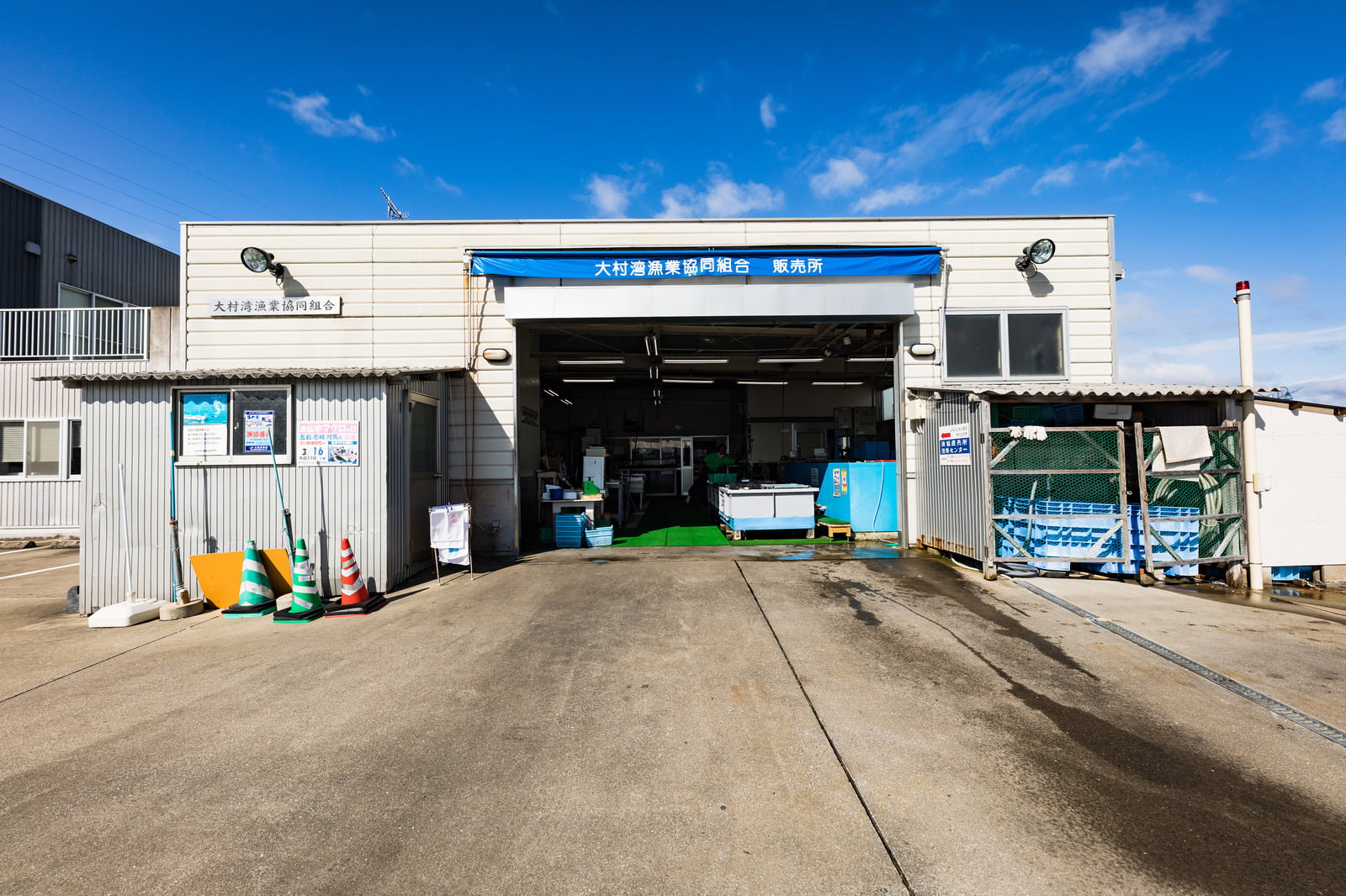 青空の下にある大村湾漁協組合の白い販売所建物