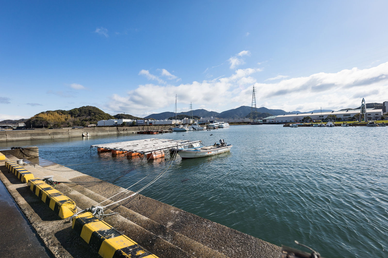 大村湾漁協組合前の漁港に停泊する白い漁船と桟橋の風景