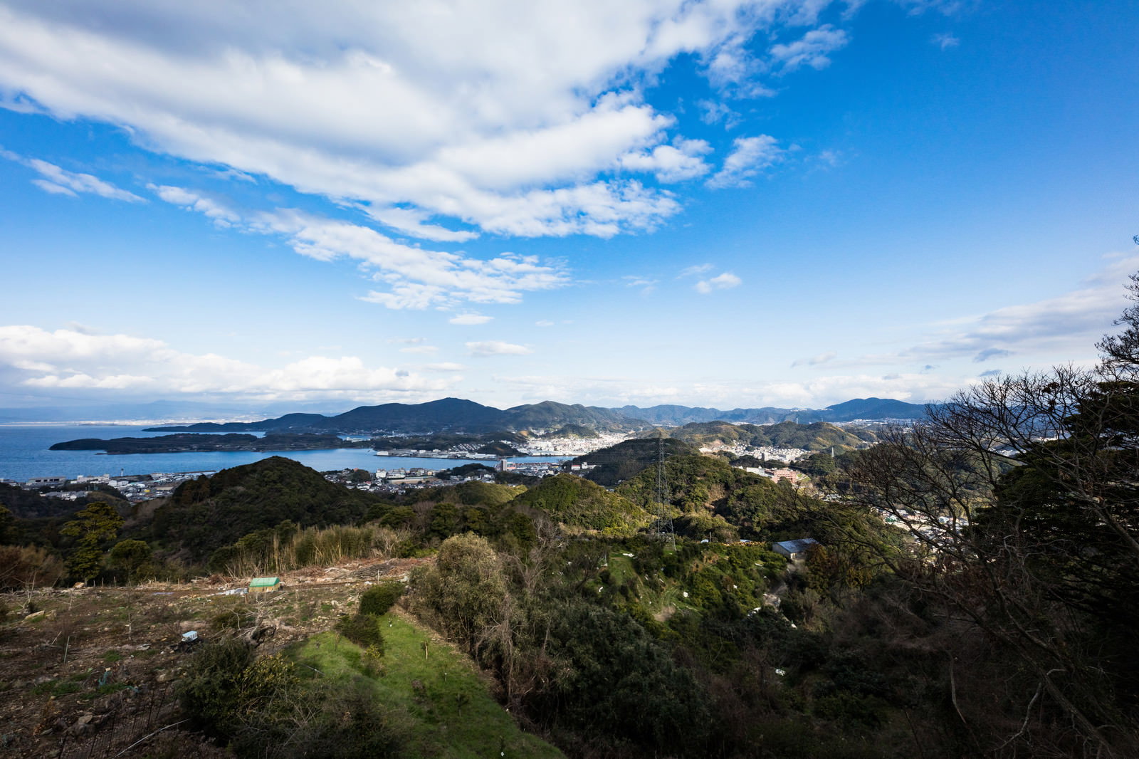 鳴鼓岳の山頂から眺める時津町の港町風景と青空