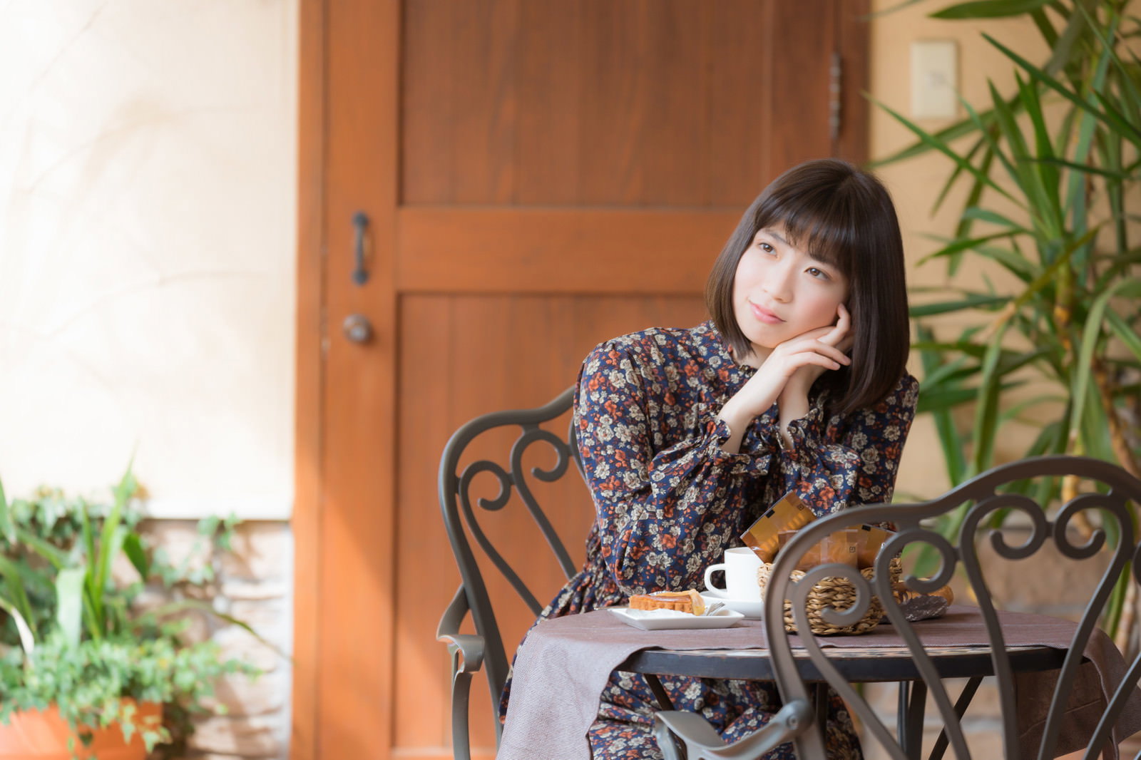 木製テーブルでコーヒーを飲みながらくつろぐ女性［モデル：塩田みう］