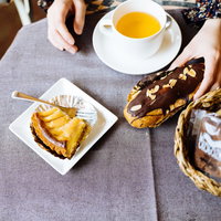 ティータイムに紅茶とエクレアのひととき、優雅な午後のカフェタイムの写真