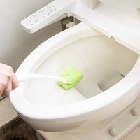 トイレの便器を緑のブラシで掃除する手元の写真