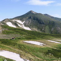 残雪の十勝岳を背景にしたホロカメットク小屋の写真