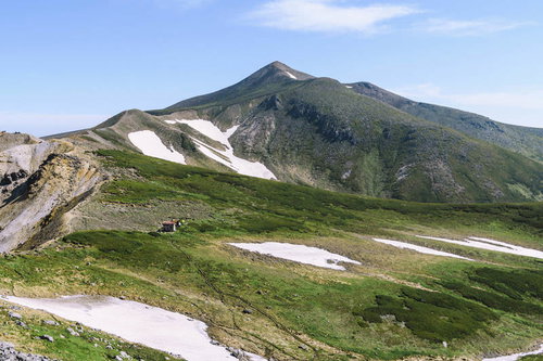 残雪の十勝岳を背景にしたホロカメットク小屋